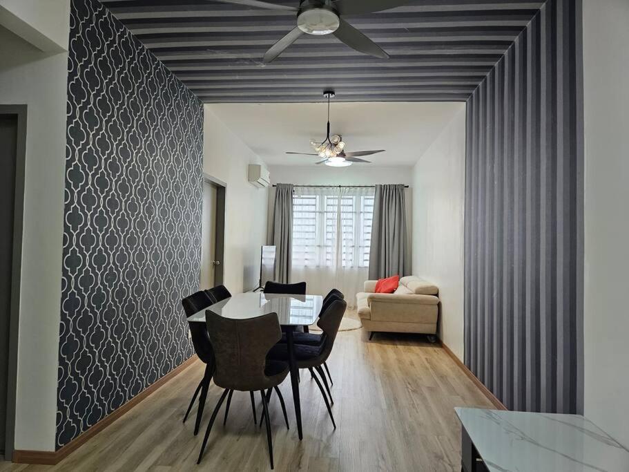 una sala da pranzo con tavolo, sedie e divano di E! Best Apartment a Padang Serai