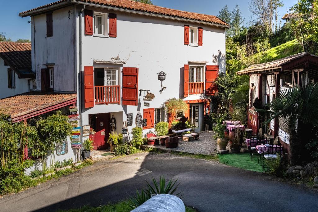 a white house with red shutters on a street at Le Moulin de Pascale in Espelette