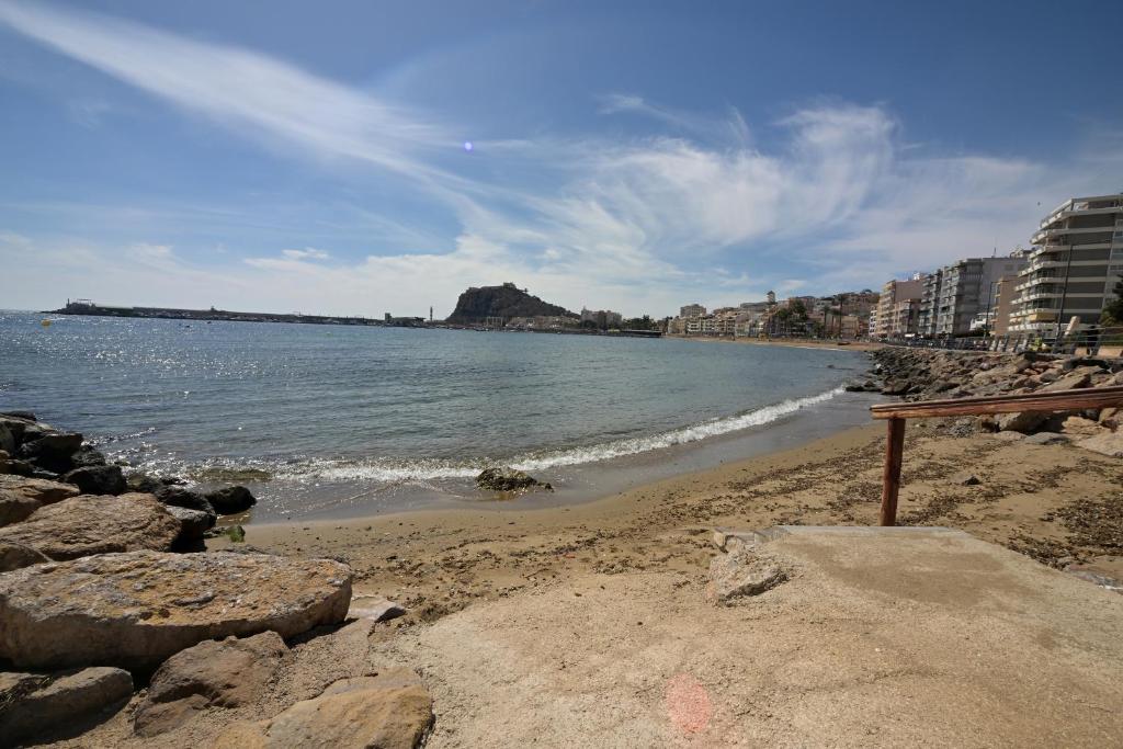 a beach with rocks and the ocean and buildings at Águilas Delicias Piscina Wifi AC Parking Gratis in Águilas