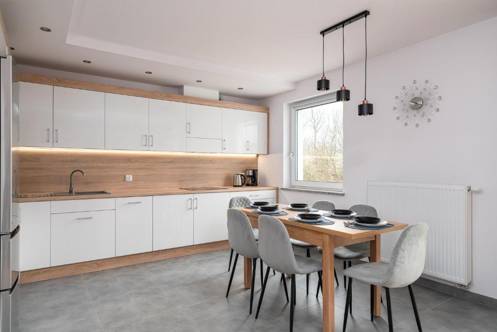 a kitchen with white cabinets and a wooden table and chairs at Apartament GOJA Podzamcze in Wałbrzych