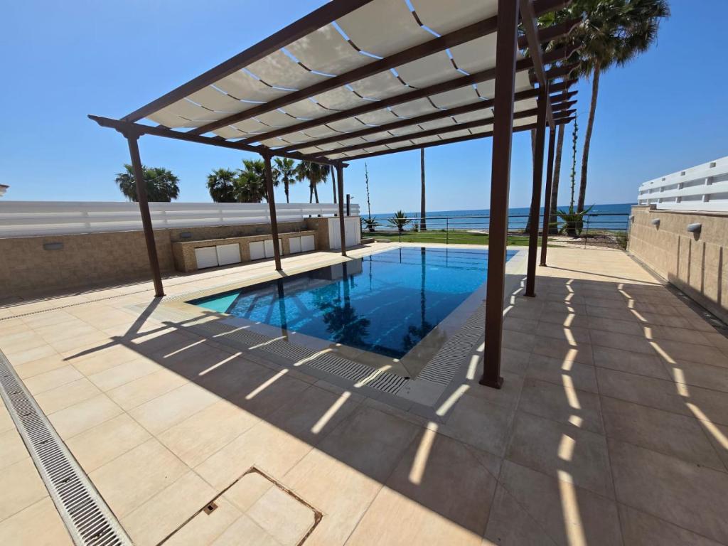 uma pérgola sobre uma piscina num pátio em Fabulous beach front house with pool em Lárnaca