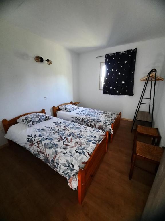2 Betten in einem kleinen Zimmer mit Fenster in der Unterkunft Chez Marc in Lubersac