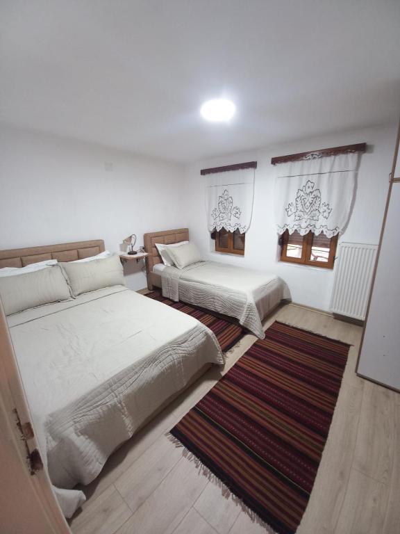 a bedroom with two beds and a rug at VodaHouse in Gjirokastër