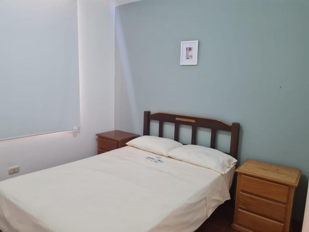 a bedroom with a large bed and a night stand at Habitaciones Matrimoniales en Playa Pulpos HOSPEDAJE DELFINES HOUSE in Lurín