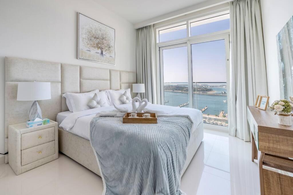 a bedroom with a bed and a desk and a large window at Elegant 1BR Apartment with Sea View and Free Beach Access in Dubai