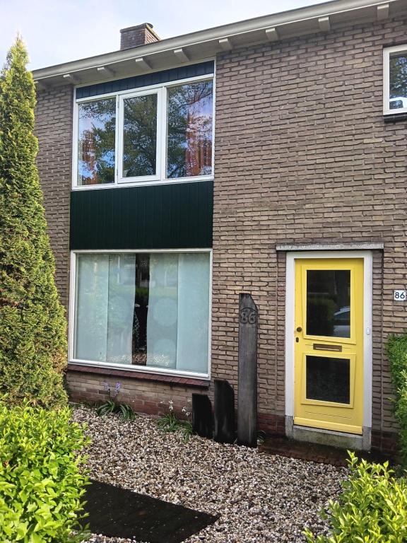 a brick house with a yellow door at Hoekhuis met tuin op het zuiden. in Gouda