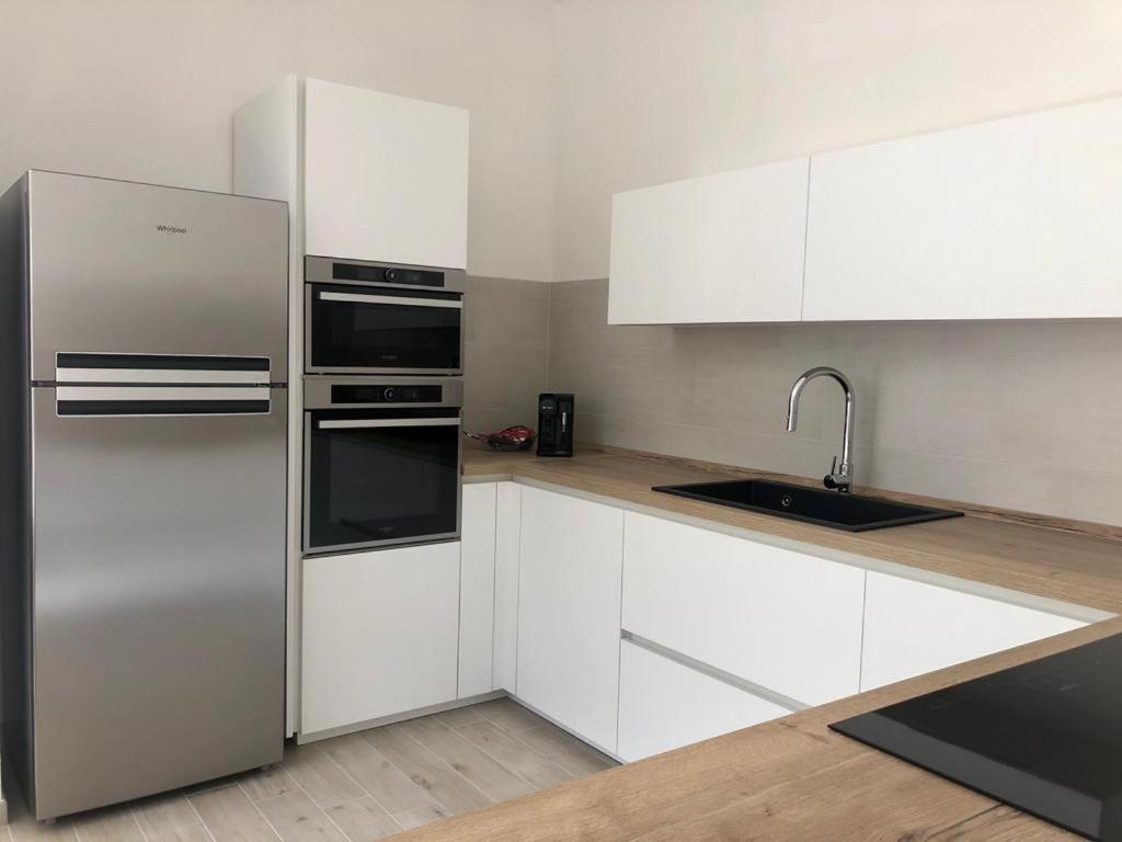 a kitchen with white cabinets and a stainless steel refrigerator at Dimora La Coccinella - Accommodation in Muravera