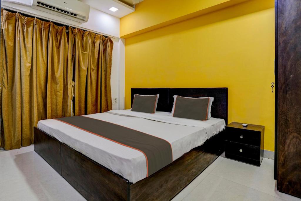 a bedroom with a large bed with yellow walls at Collection O Rio Corporate House in Mumbai