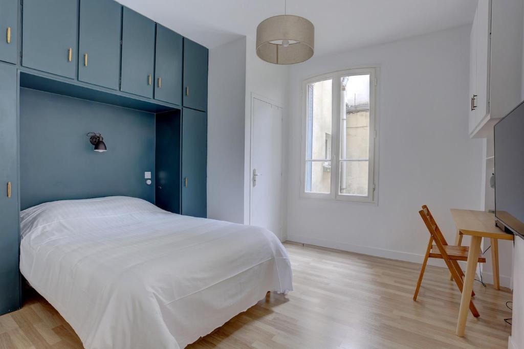 um quarto com armários azuis, uma cama e uma secretária em La Paroisse - Versailles em Versailles