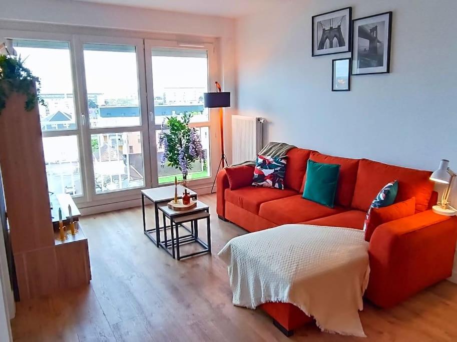 un salon avec un canapé rouge et une table dans l'établissement Appartement neuf - 3 chambres - 6 personnes - 73m² vue sur la ville, à Caen