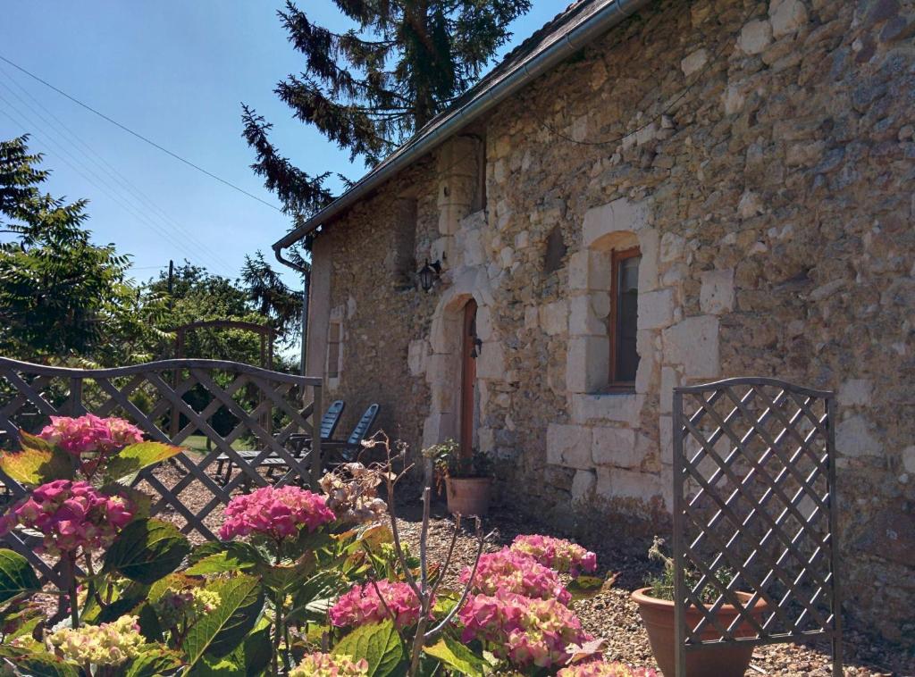 una casa de piedra con dos sillas y flores delante de ella en La Source, en Sermaise