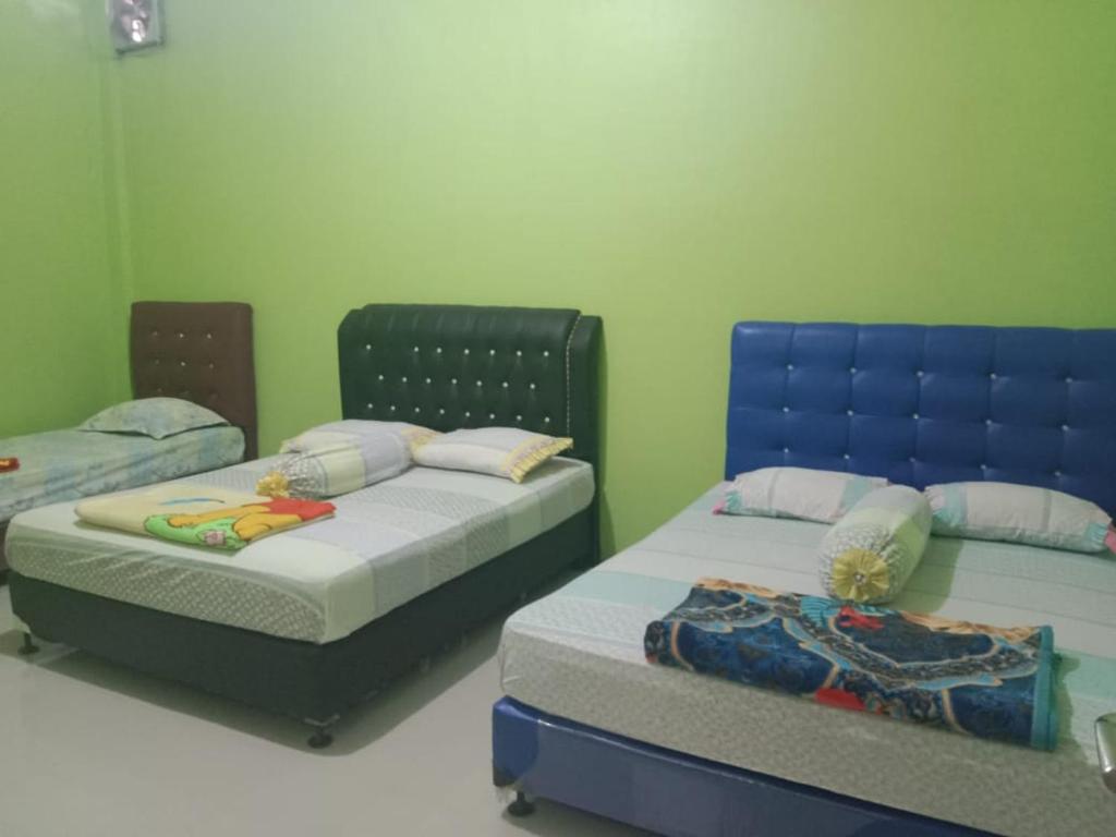 two beds in a room with green walls at penginapan alleo in Duku