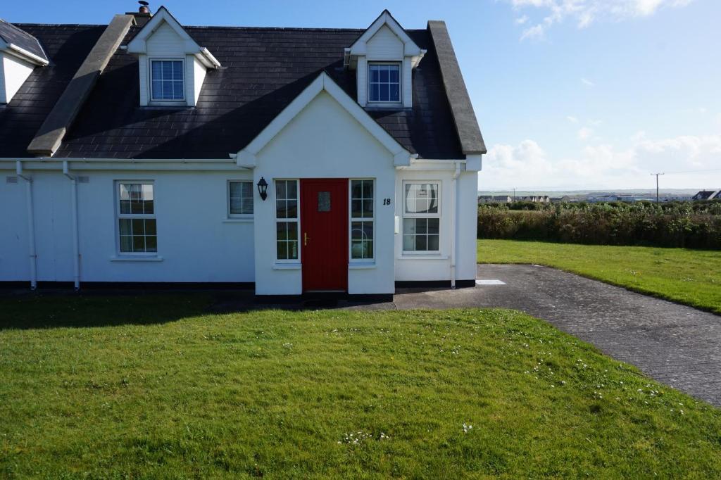 a white house with a red door at 18 Ballybunion Holiday Cottages in Ballybunion