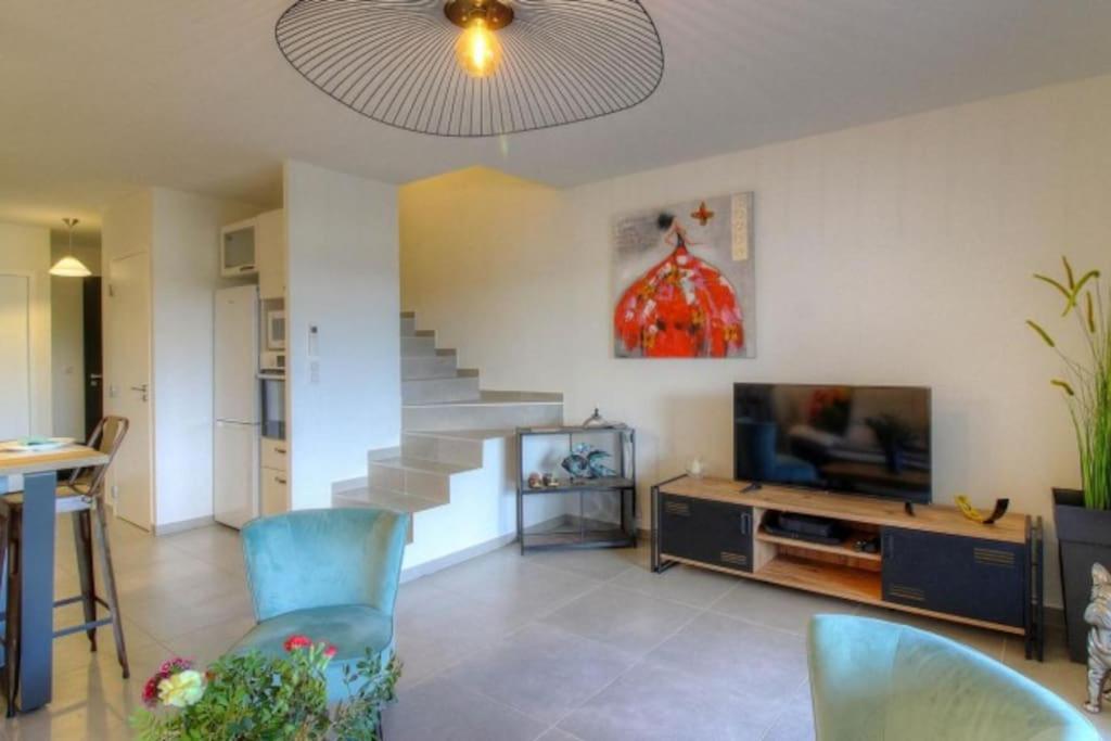 a living room with a staircase and a television at Villa moderne Cala Rossa Bay Les Oceanides in Lecci