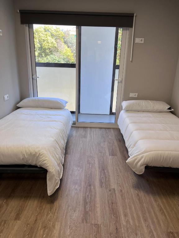 2 Betten in einem Zimmer mit einem großen Fenster in der Unterkunft Unicorn Residence for students New Opening 2024 in Valencia