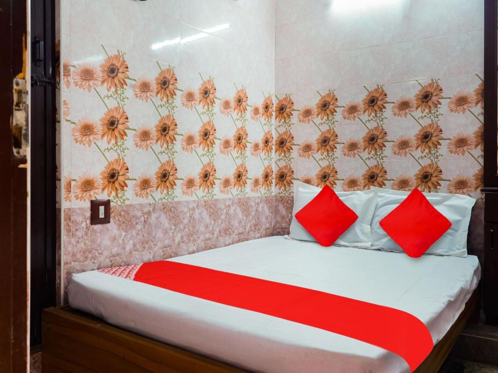 um quarto com uma cama com almofadas vermelhas e uma parede floral em OYO Flagship Ks Elite em Madurai