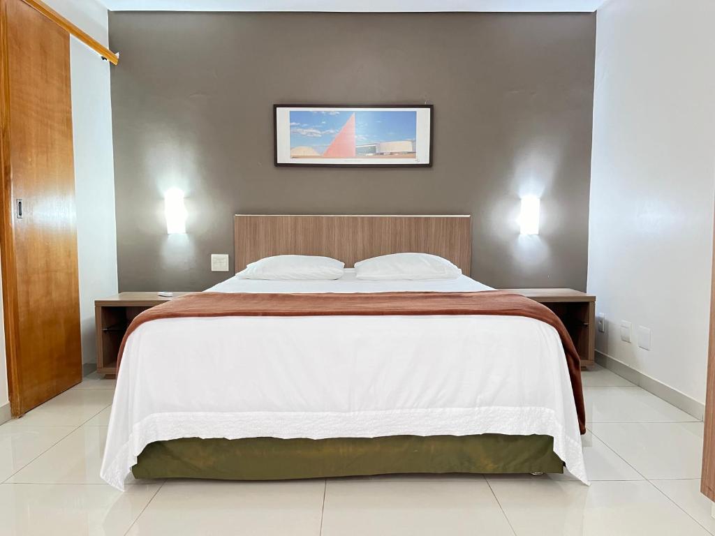 1 dormitorio con 1 cama grande con sábanas blancas en Flat 2313 - Crystal Place, en Goiânia