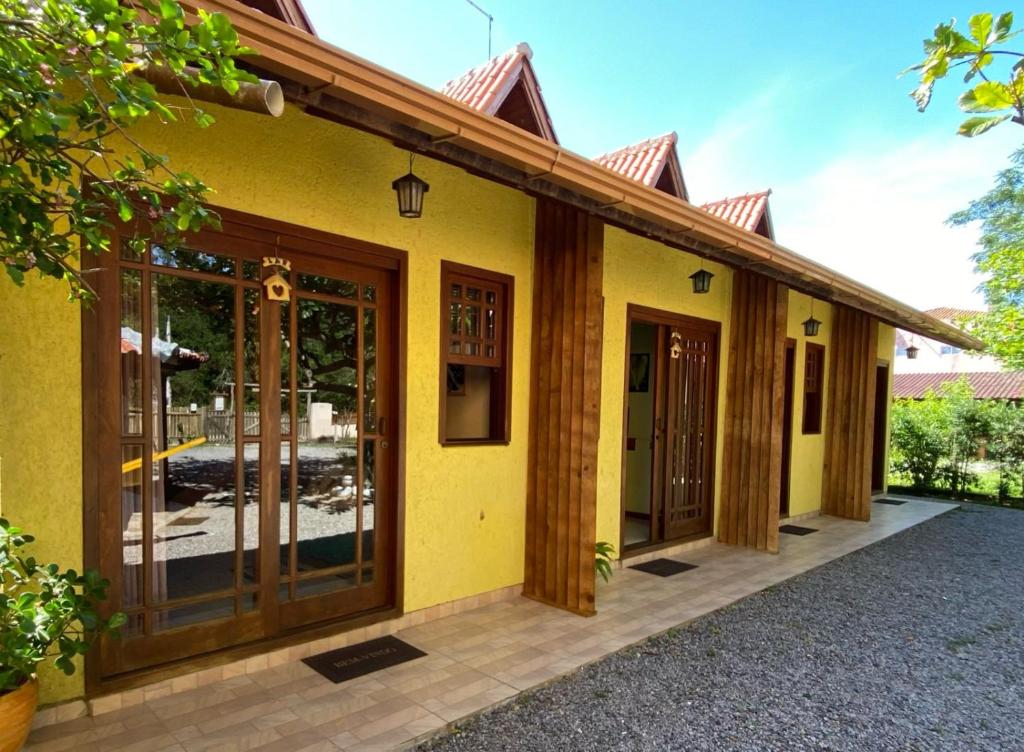 a yellow house with sliding glass doors at Pousada Chalé Caminho da Guarda in Palhoça