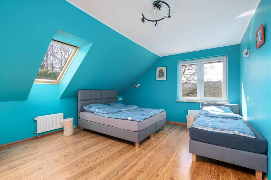 2 łóżka w pokoju z niebieskimi ścianami i drewnianą podłogą w obiekcie Dom Na Skarpie w Wałbrzychu