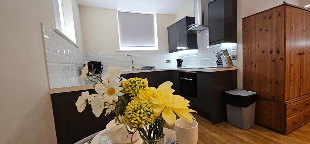 una cocina con un jarrón de flores sobre una mesa en Modern Studio apartment in Town center en Ipswich