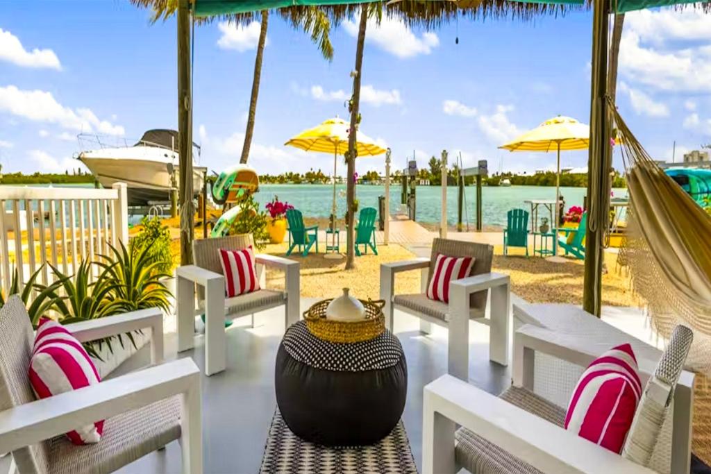 a patio with chairs and a hammock and the water at Carpe Diem - Seas The Day in Key Colony Beach