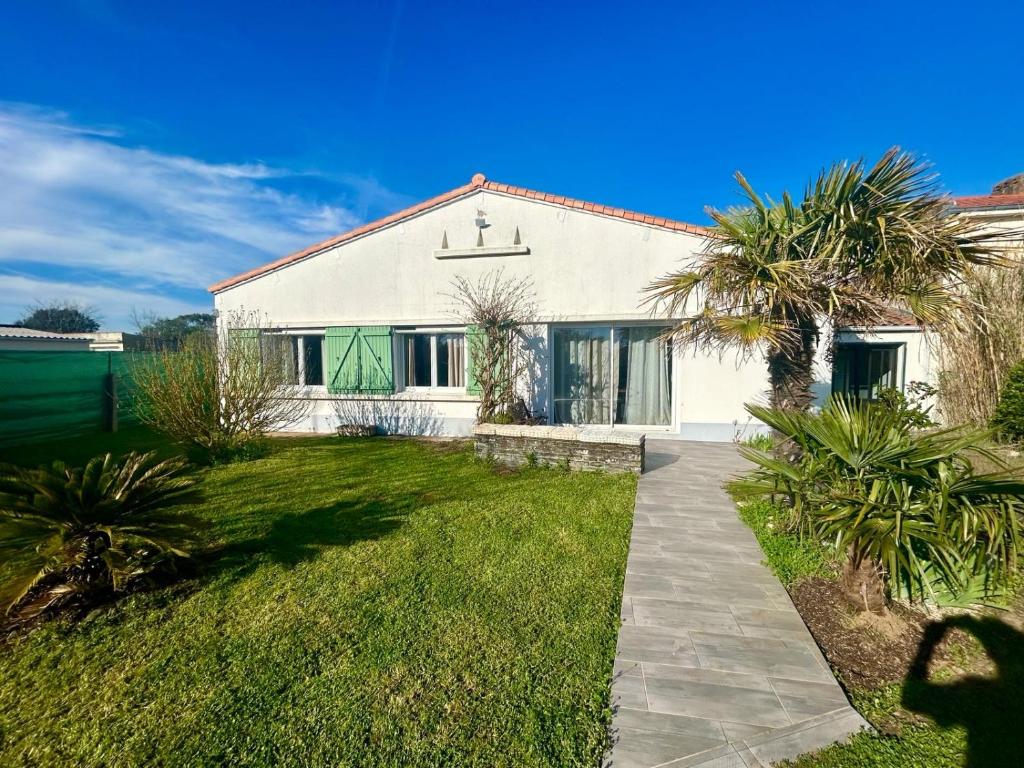 una casa blanca con palmeras delante en Maison de vacances en Olonne-sur-Mer