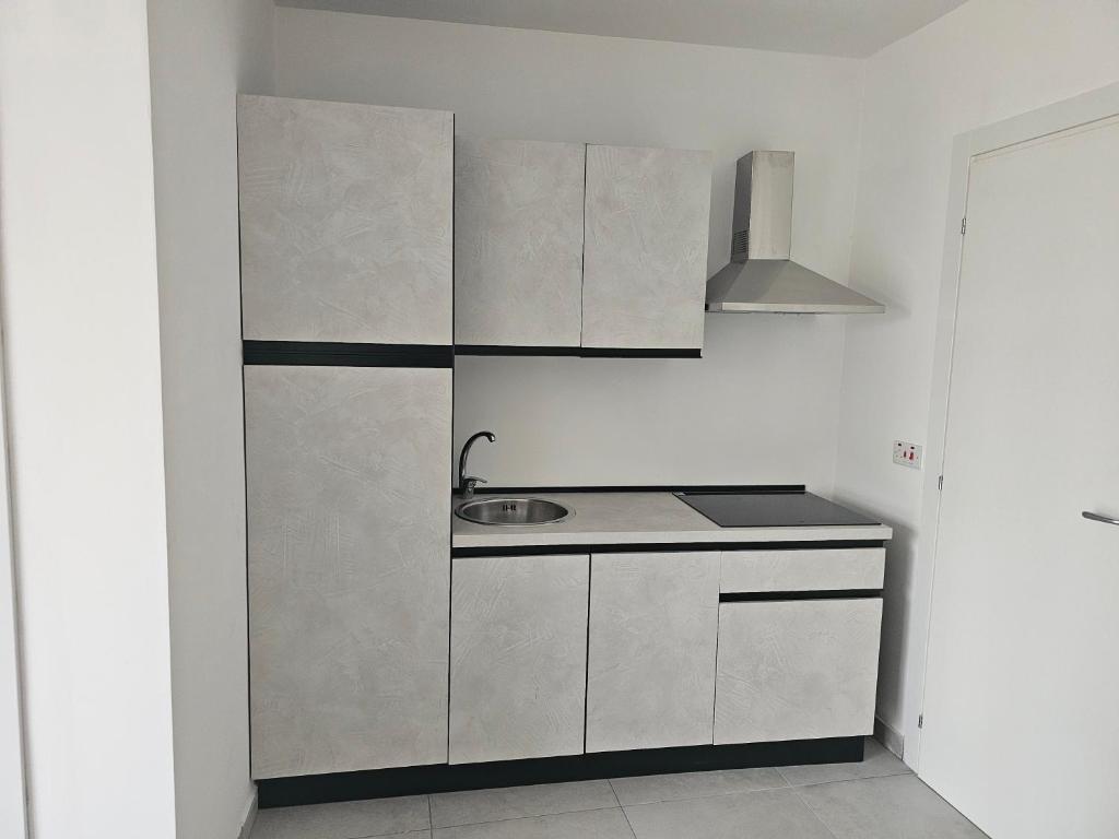 una cocina con armarios blancos y fregadero en One bedroom apartment Msida, en Msida