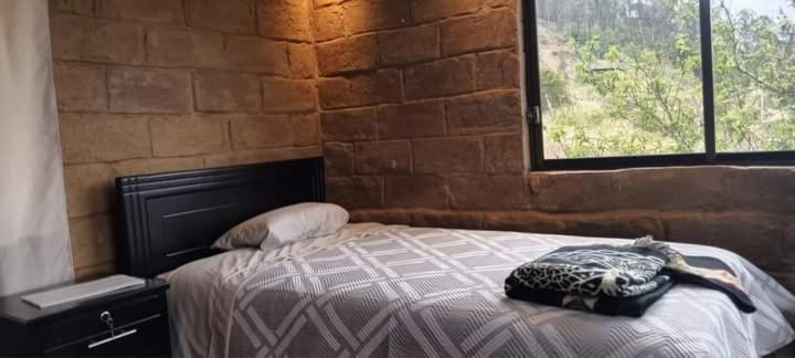 a bedroom with a bed and a brick wall at Hospedaje Leonor in Cuenca