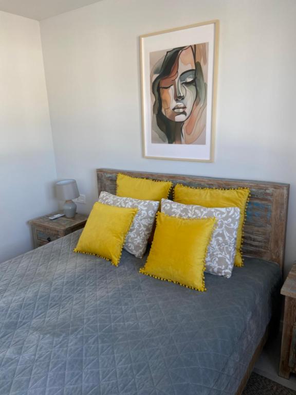 Un dormitorio con una cama con almohadas amarillas y una pintura en Villa Playa de Turmalina - Denia El Verger, en El Verger
