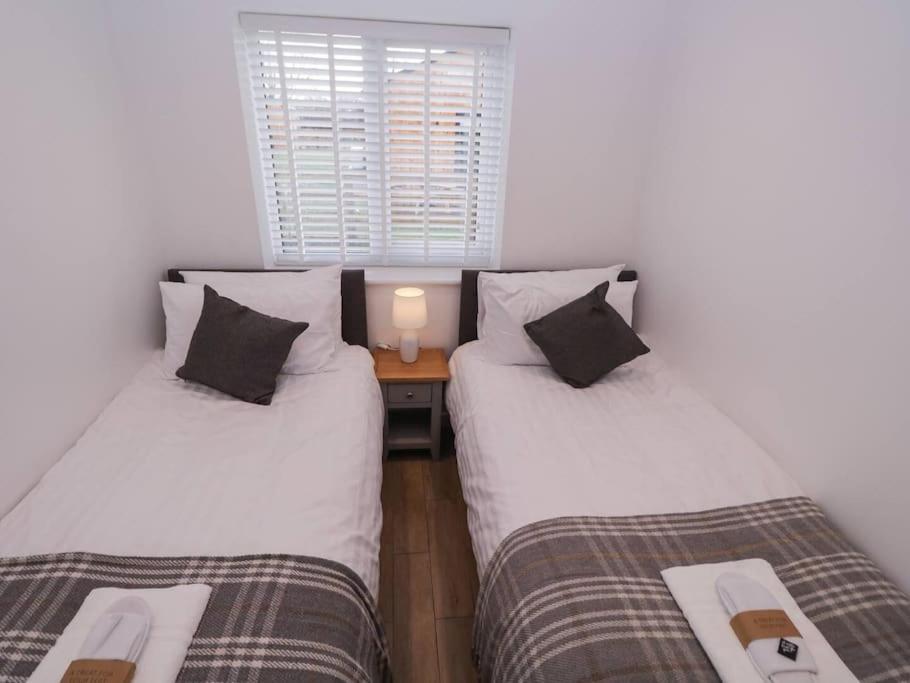 two twin beds in a room with a table at Ash Lodge in Ashbourne