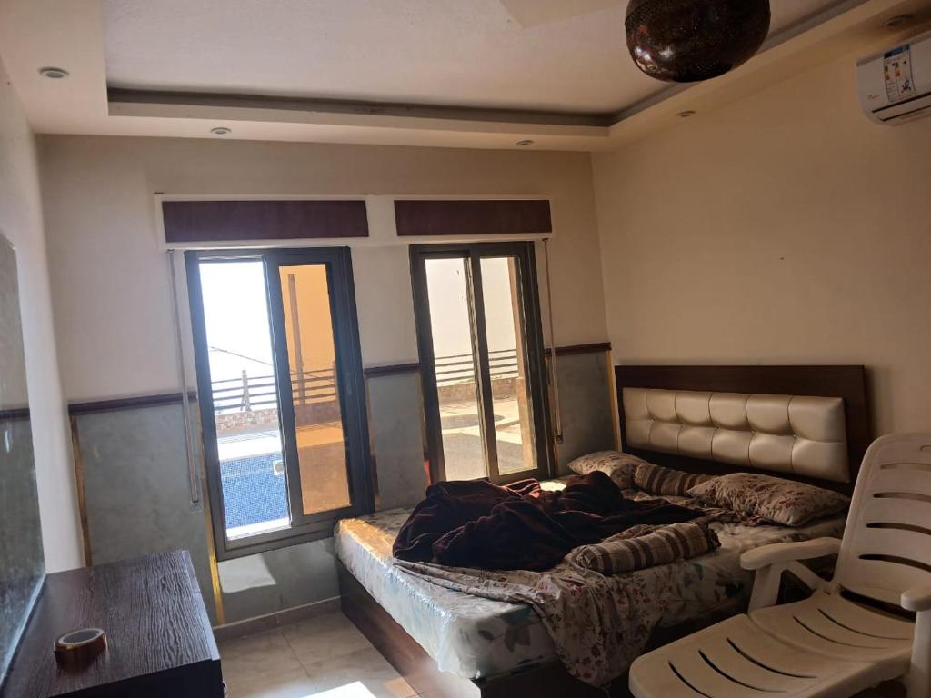 a bedroom with a bed and a table and two windows at شاليه للايجار اليومي والاسبوعي in Amman