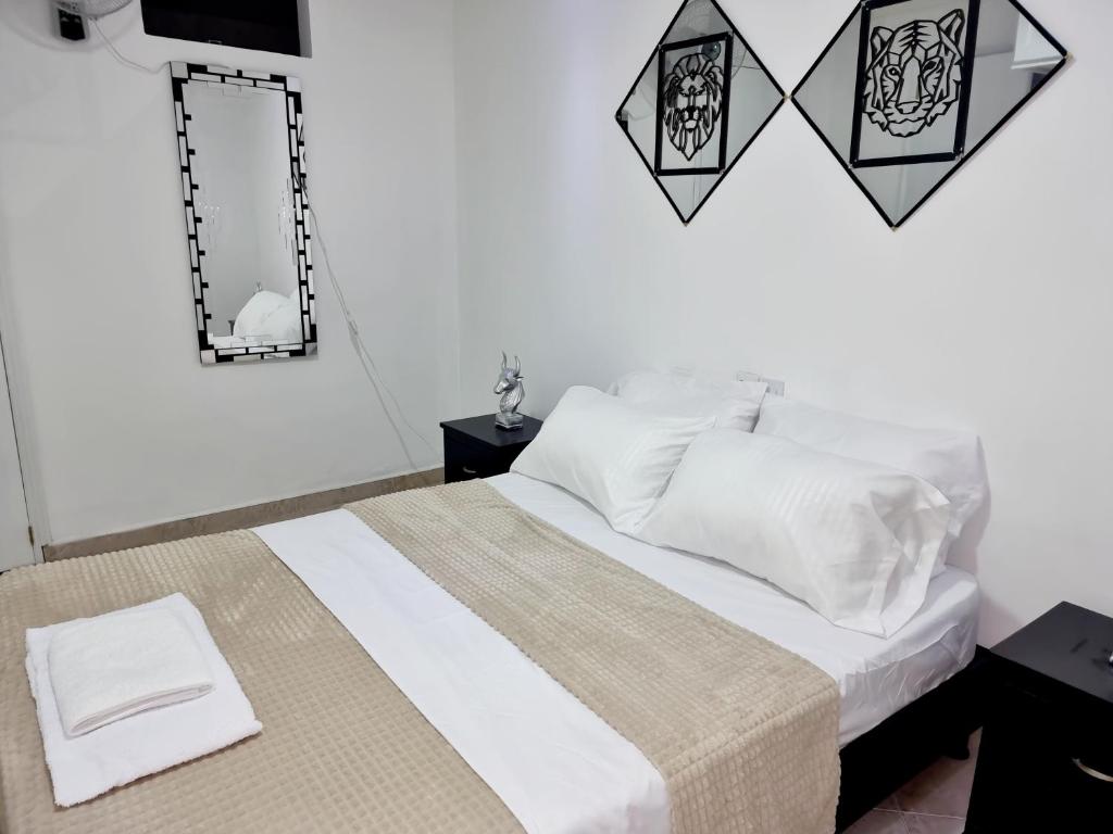 um quarto com uma cama com lençóis brancos e um espelho em Habitación amplia y cómoda con baño privado em Bucaramanga