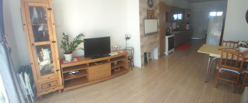 a living room with a television on a wooden dresser at Pousada 4 estações in Machadinho
