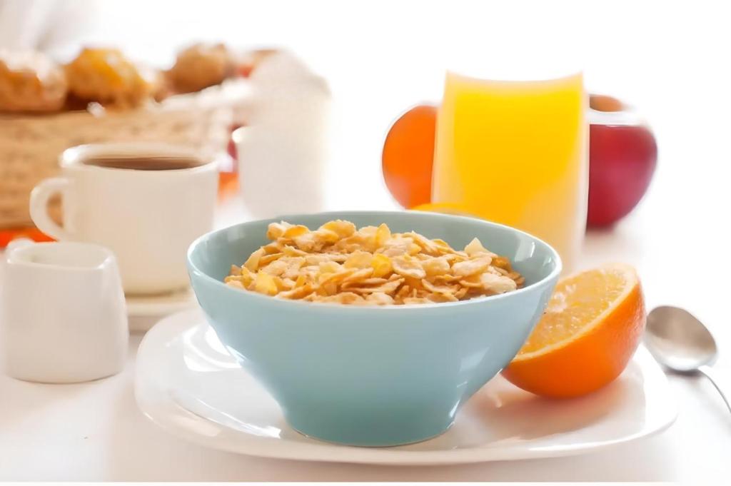 a bowl of cereal and a cup of coffee and an orange at Modern ground floor apartment with free parking very near centre in Ripon