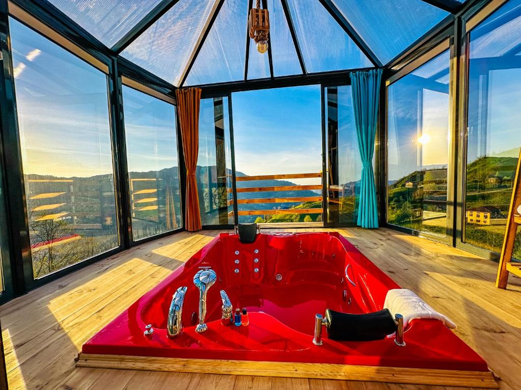 uma banheira vermelha num quarto com janelas em Organic village bungalow em Ayder Yaylasi