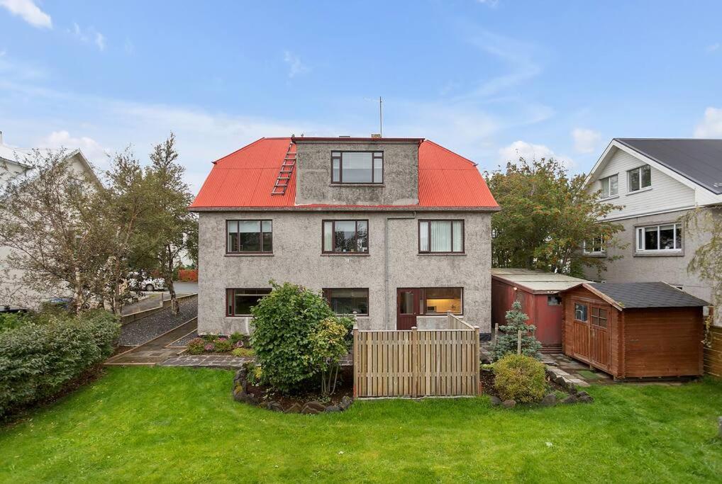 een huis met een rood dak in een tuin bij Stylish Apartment Retreat Near Downtown in Reykjavík