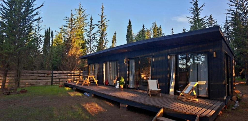 a black house with a wooden deck and chairs at Casa cercana a playas y bosque in Valparaíso
