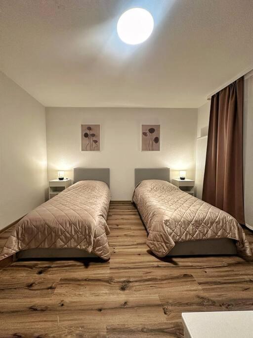 E&K Apartment II في دوسلدورف: سريرين في غرفة نوم مع أرضيات خشبية