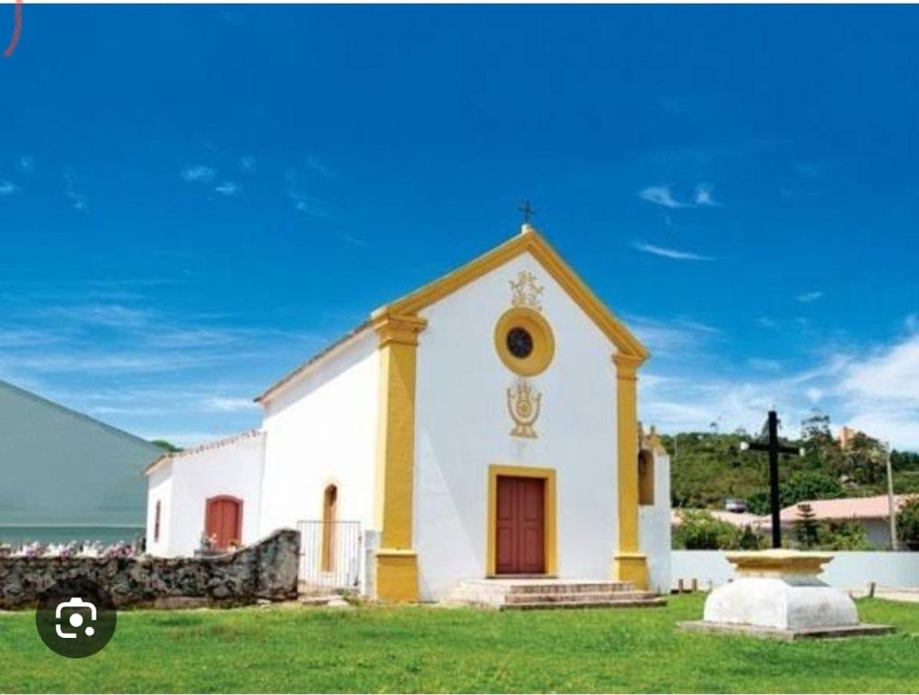 a small white and yellow church on a grass field at Residencial Marémansa pousada apto 01 in Governador Celso Ramos