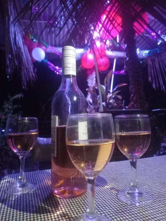 a bottle of wine and two glasses on a table at Sea Side Elvis HomeStay in Korotogo