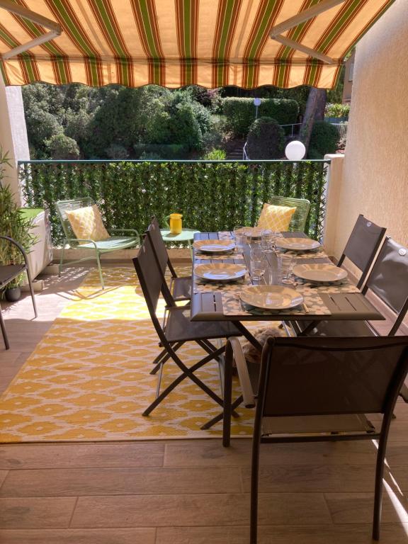 Une table à manger et des chaises sont disponibles sur la terrasse. dans l'établissement STUDIO 110 GRANDE TERRASSE PROCHE MER, à Bandol