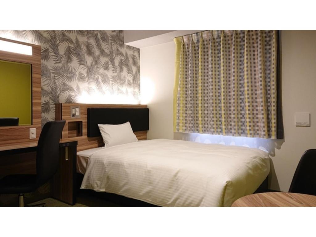 Schlafzimmer mit einem Bett, einem Schreibtisch und einem Fenster in der Unterkunft Green Rich Hotel Okinawa Nago - Vacation STAY 55410v in Nago