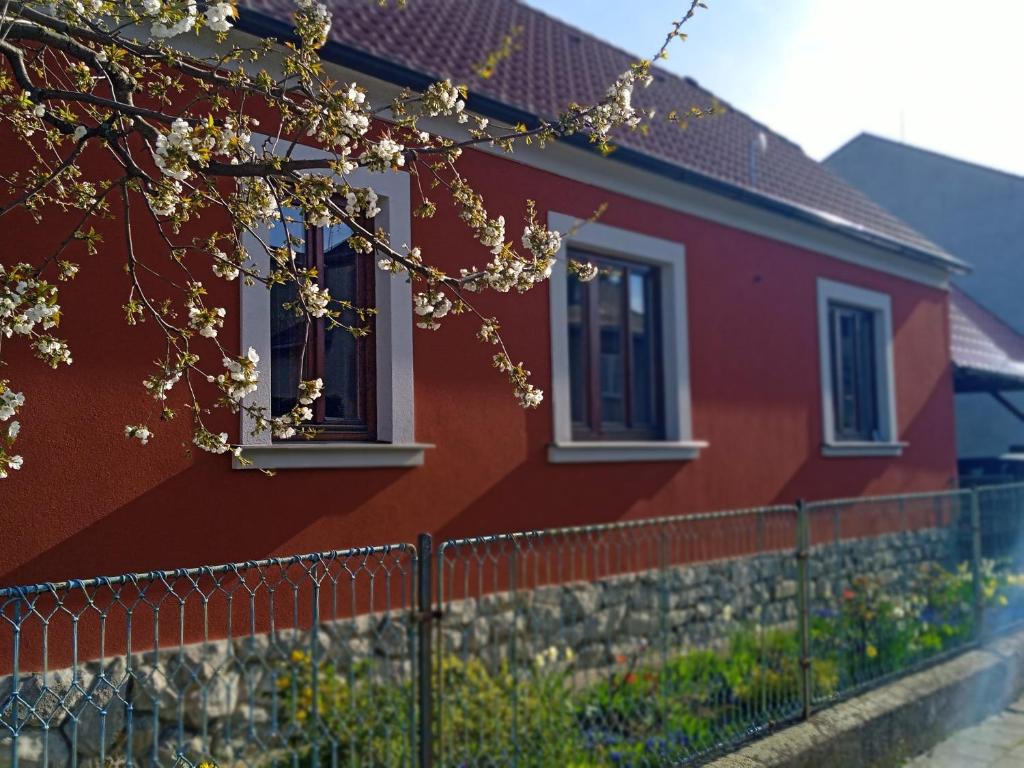 a red house with white windows and a fence at Chalupa Na Polní in Jemnice