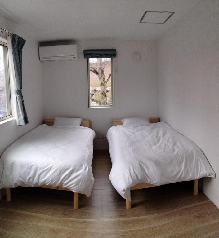 two beds in a room with white sheets and a window at Guesthouse Senba - Vacation STAY 16651 in Mito