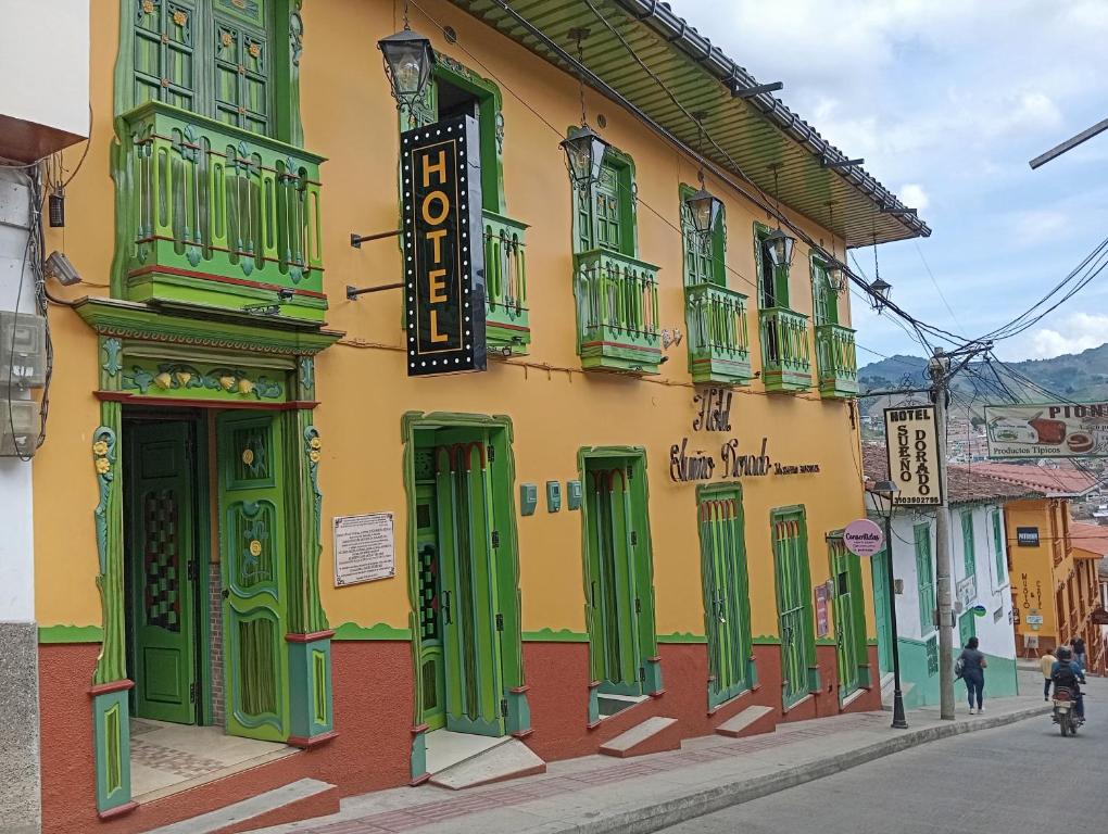 un edificio con puertas verdes y ventanas en una calle en HotelSueño Dorado Aguadas, en Aguadas