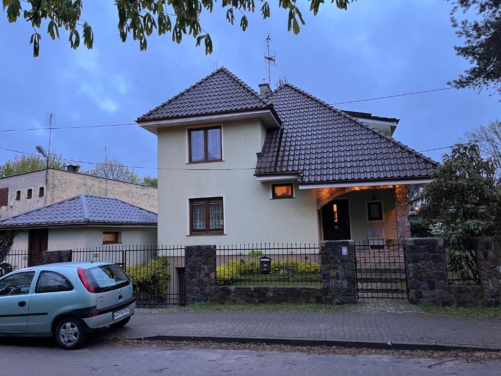 biały dom z zaparkowanym przed nim samochodem w obiekcie Pokoje u Igi w Gdańsku