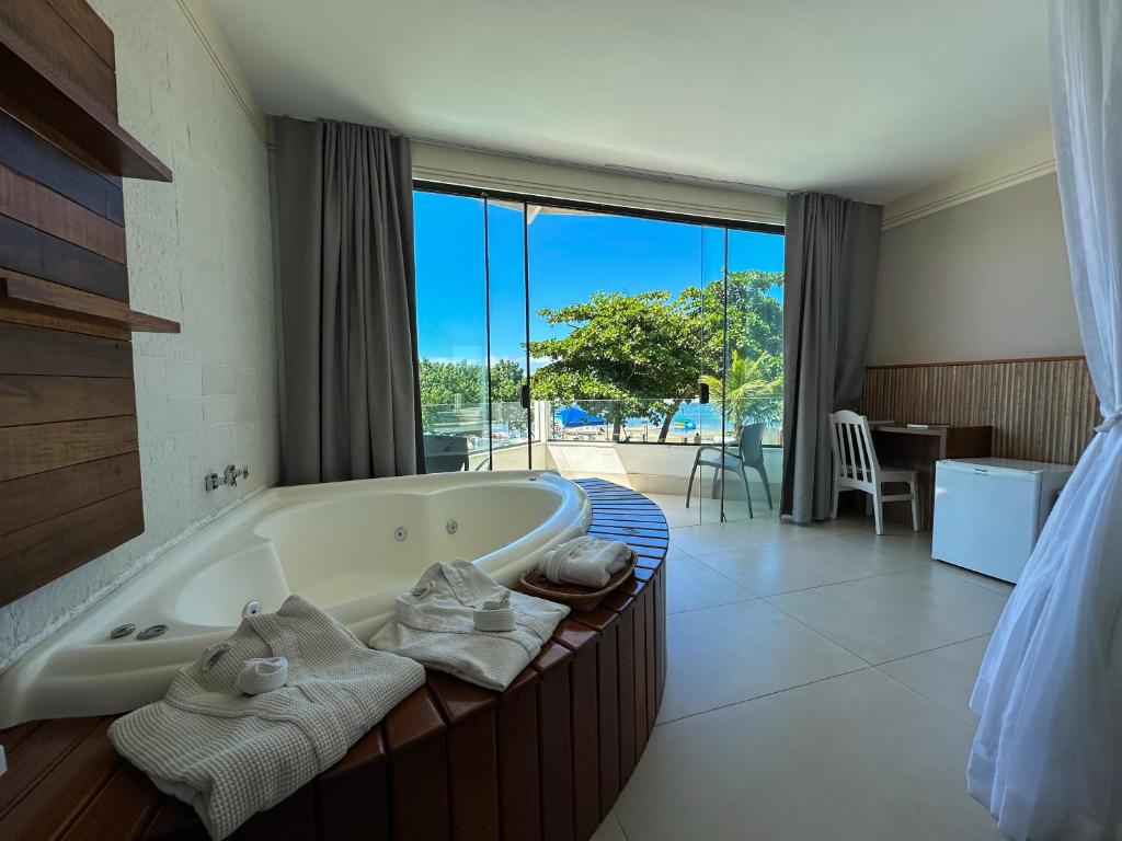 a bathroom with a bath tub with a large window at Passagem Concept Hotel e Spa in Cabo Frio