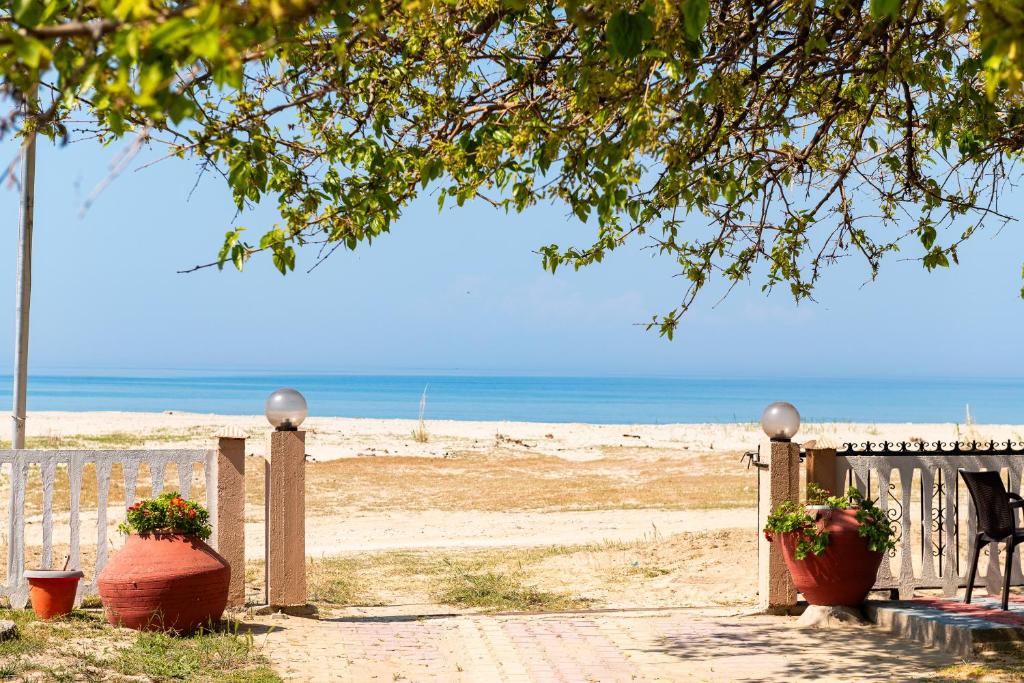 a beach with a fence and a bench and flowers at Lampiris Beach Front Apartments in Potos