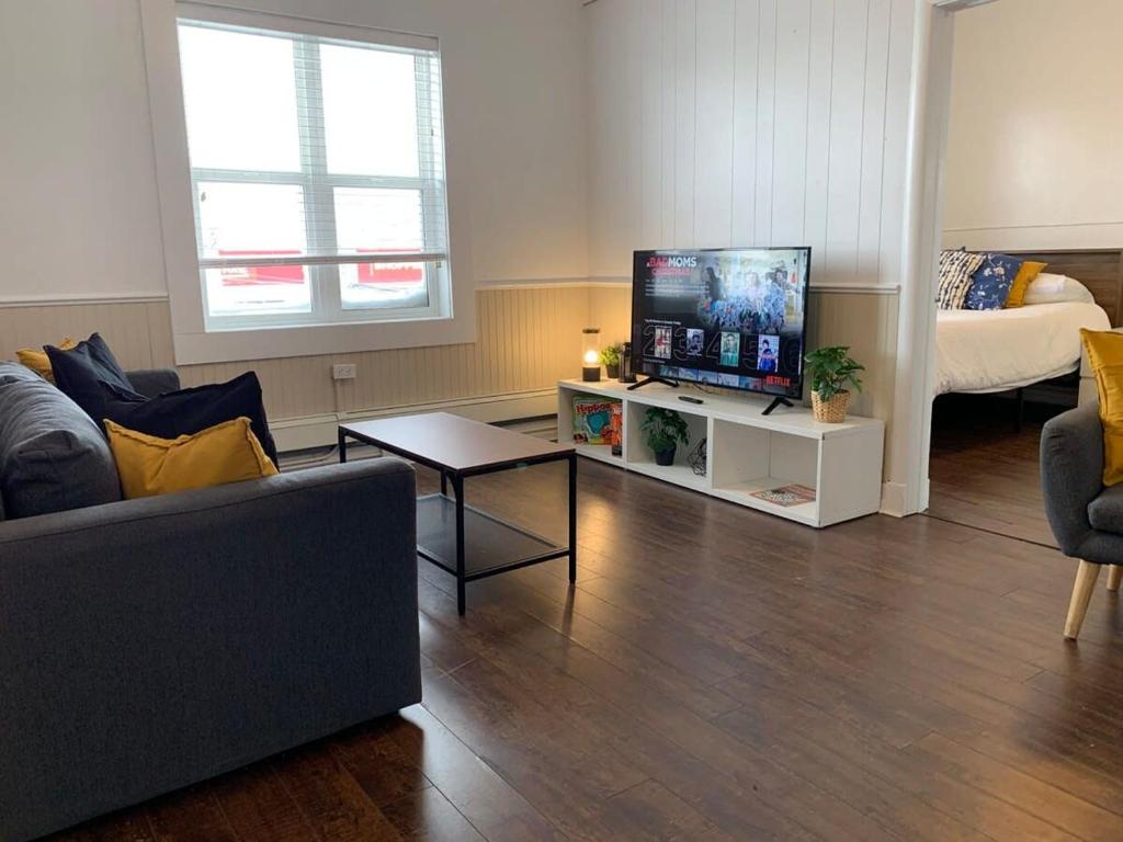 uma sala de estar com um sofá e uma televisão de ecrã plano em Large 1-bedroom Condo l Downtown l WiFi & Smart TV em Moose Jaw