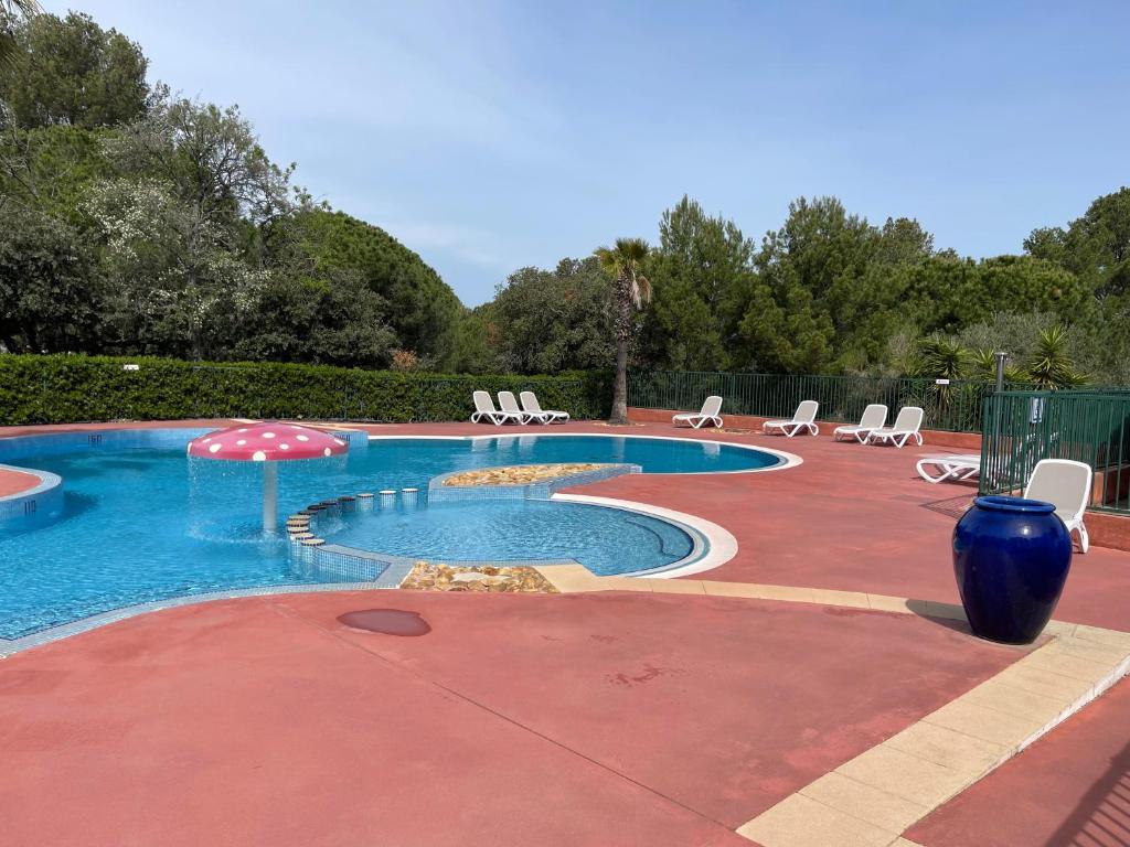 a pool with chairs and an umbrella on a patio at Chalet T3 4/6 personnes à Agde in Agde